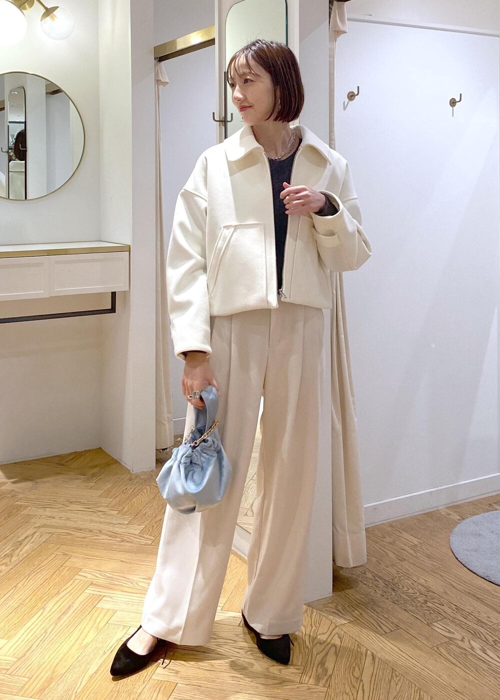 ブルー系のハンドバッグ、ホワイト系のブルゾン、ブラック系のパンプスを着用したレディースの冬コーディネートの2枚目の写真