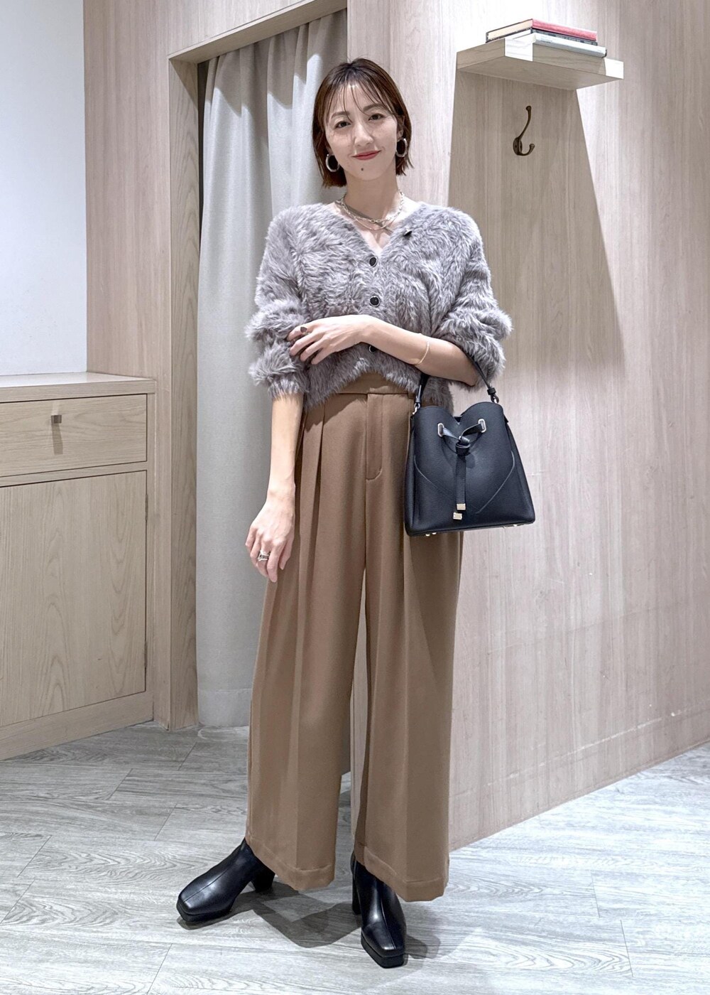 ブラック系のショルダーバッグ、グレー系のカーディガン/ボレロ、ブラック系のブーツを着用したレディースの秋コーディネートの4枚目の写真