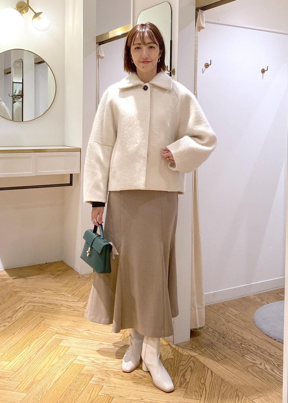 ホワイト系のブーツ、ベージュ系のスカート、ホワイト系のその他アウターを着用したレディースの秋コーディネートの6枚目の写真