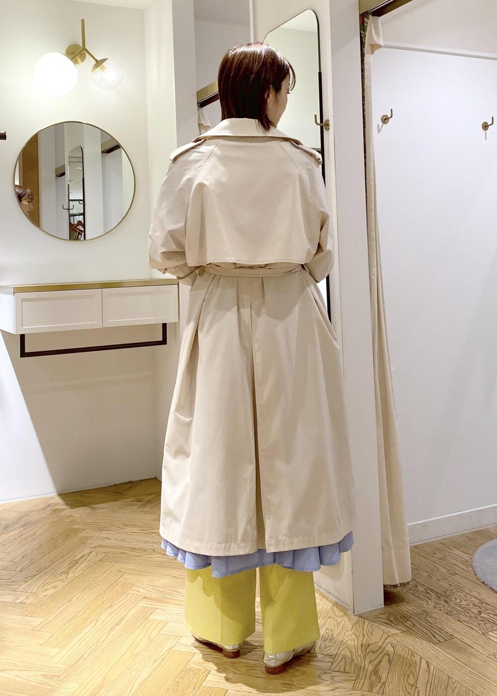 シルバー系のパンプス、ブルー系のシャツワンピース、ホワイト系のトレンチコートを着用したレディースの春コーディネートの5枚目の写真