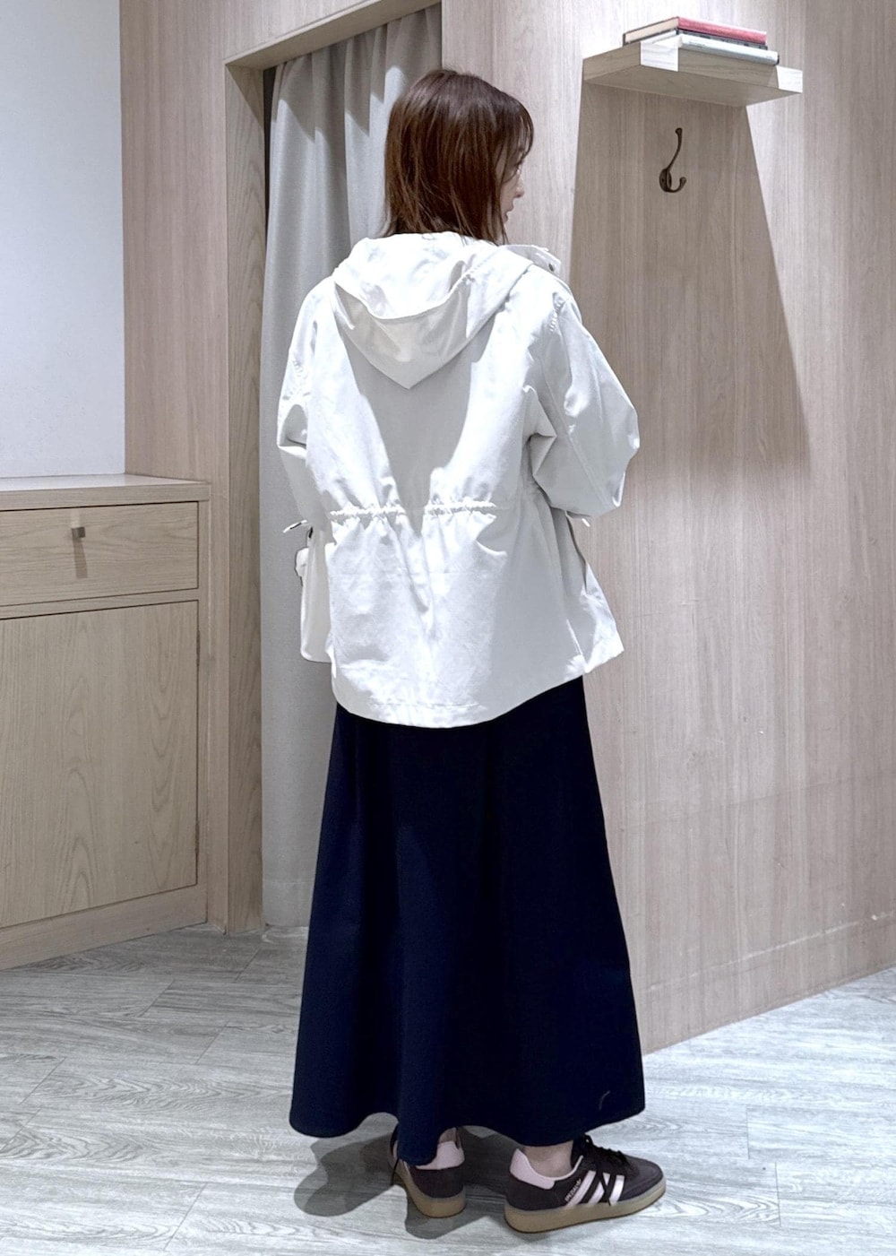 グレー系のニット/セーター、ブルー系のスカート、ホワイト系のナイロンジャケットを着用したレディースの春コーディネートの5枚目の写真