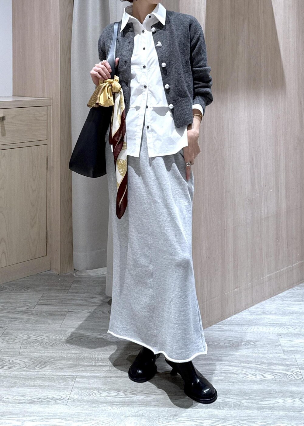 ブラック系のトートバッグ、グレー系のスカート、ホワイト系のシャツ/ブラウスを着用したレディースの秋コーディネートの2枚目の写真