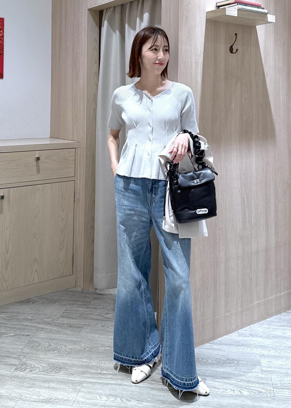 ブルー系のデニムパンツ、ホワイト系のパンプス、ブラック系のショルダーバッグを着用したレディースの春コーディネートの3枚目の写真