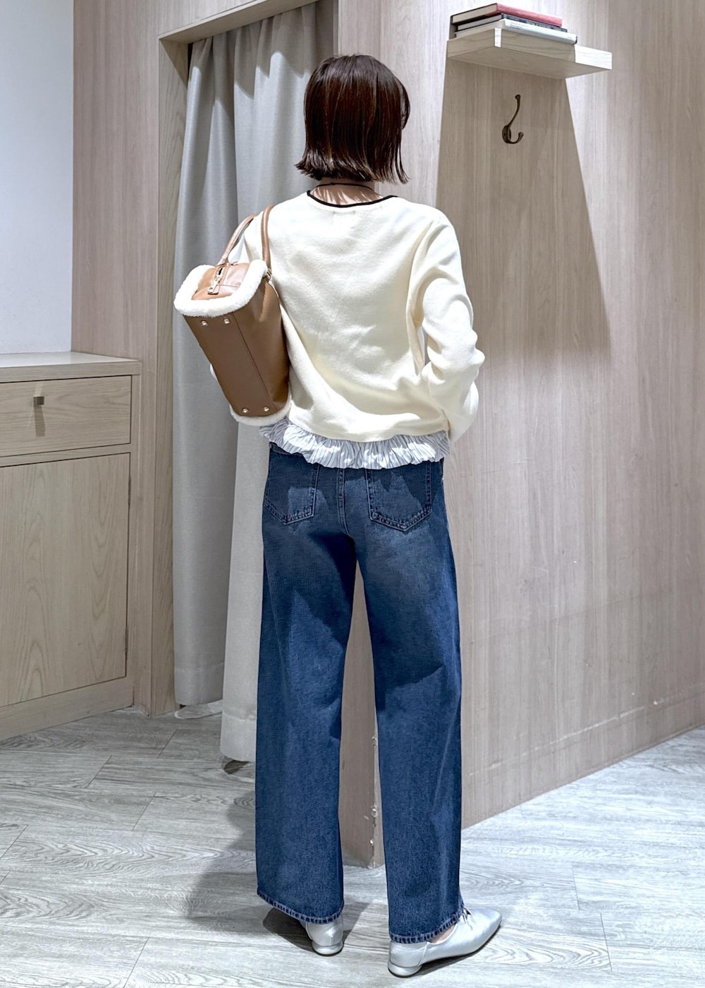 シルバー系のパンプス、ブルー系のデニムパンツ、イエロー系のボストンバッグを着用したレディースの秋コーディネートの5枚目の写真