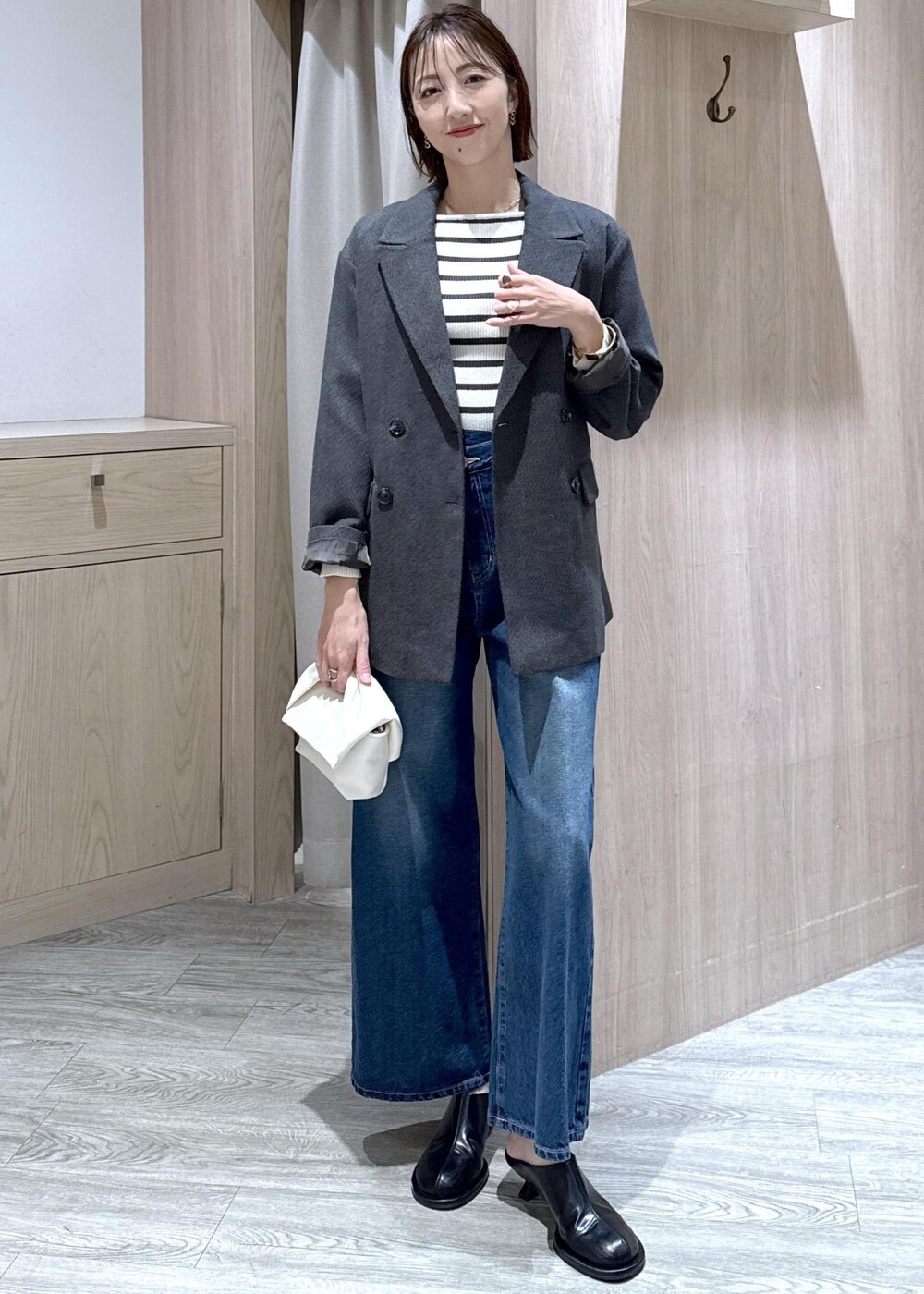 ブルー系のデニムパンツ、グレー系のテーラードジャケット、ホワイト系のショルダーバッグを着用したレディースの冬コーディネートの3枚目の写真