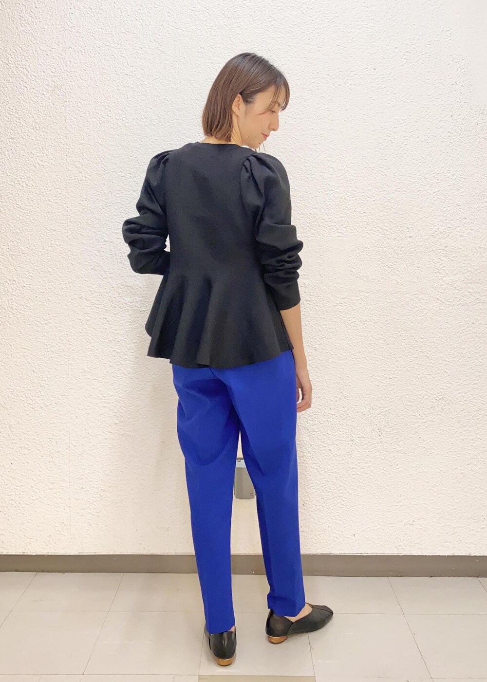 ブラック系のニット/セーター、ブルー系のスラックス、ゴールド系のチョーカーを着用したレディースの冬コーディネートの2枚目の写真