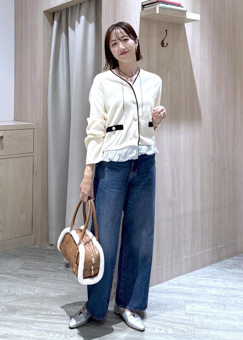シルバー系のパンプス、ブルー系のデニムパンツ、イエロー系のボストンバッグを着用したレディースの秋コーディネートの2枚目の写真