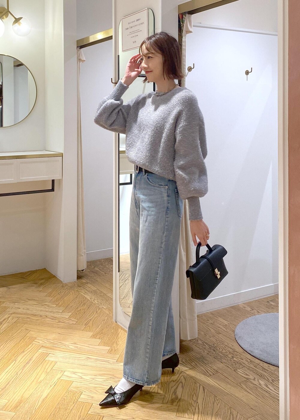 ブラック系のパンプス、グレー系のニット/セーター、ブルー系のデニムパンツを着用したレディースの冬コーディネートの3枚目の写真