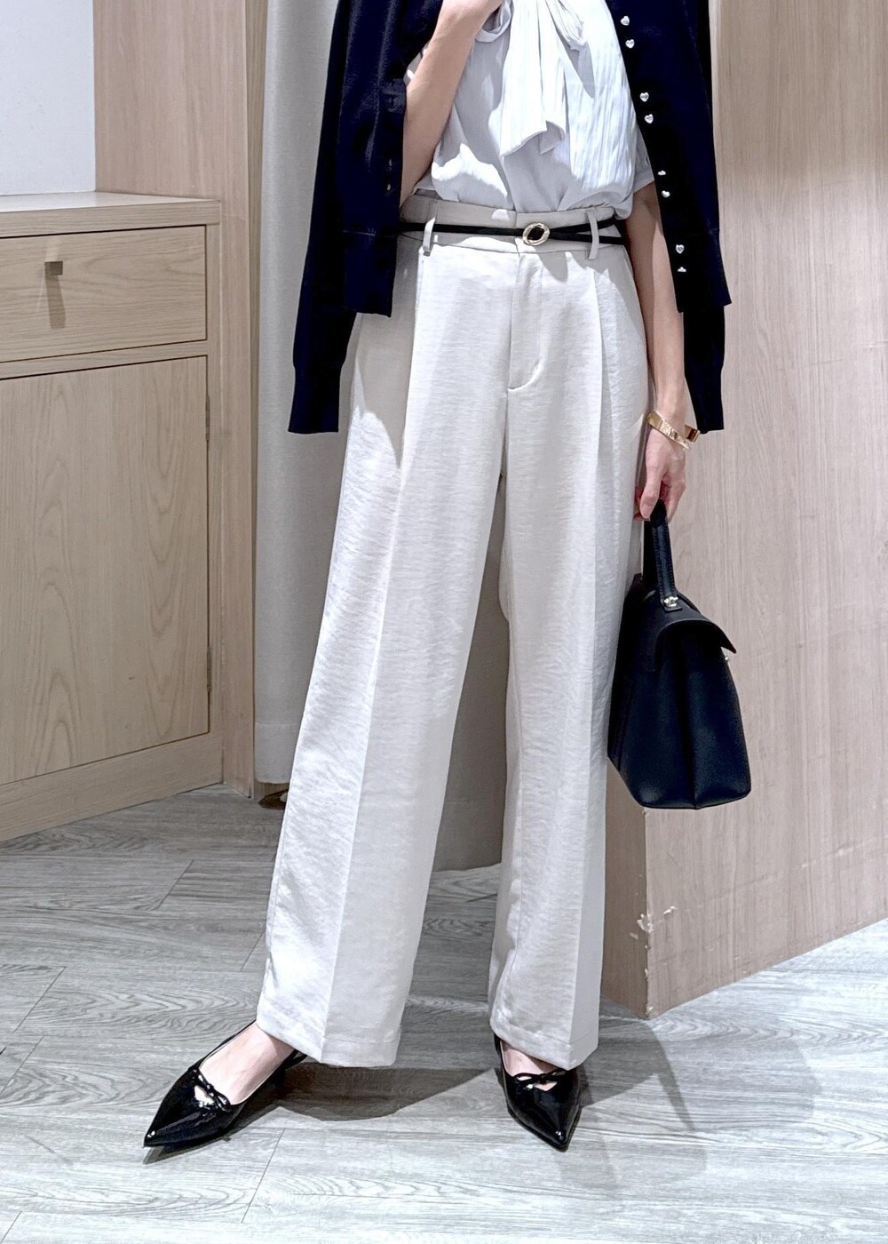 ブラック系のハンドバッグ、ブラック系のカーディガン/ボレロ、ブラック系のパンプスを着用したレディースの春コーディネートの4枚目の写真