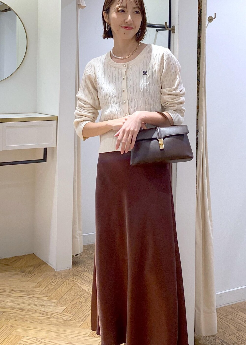 ブラウン系のスカート、ホワイト系のカーディガン/ボレロ、ブラック系のパンプスを着用したレディースの冬コーディネートの4枚目の写真