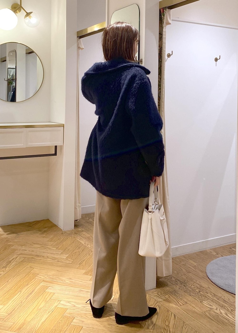 ホワイト系のショルダーバッグ、ベージュ系のスラックス、グレー系のカーディガン/ボレロを着用したレディースの冬コーディネートの3枚目の写真