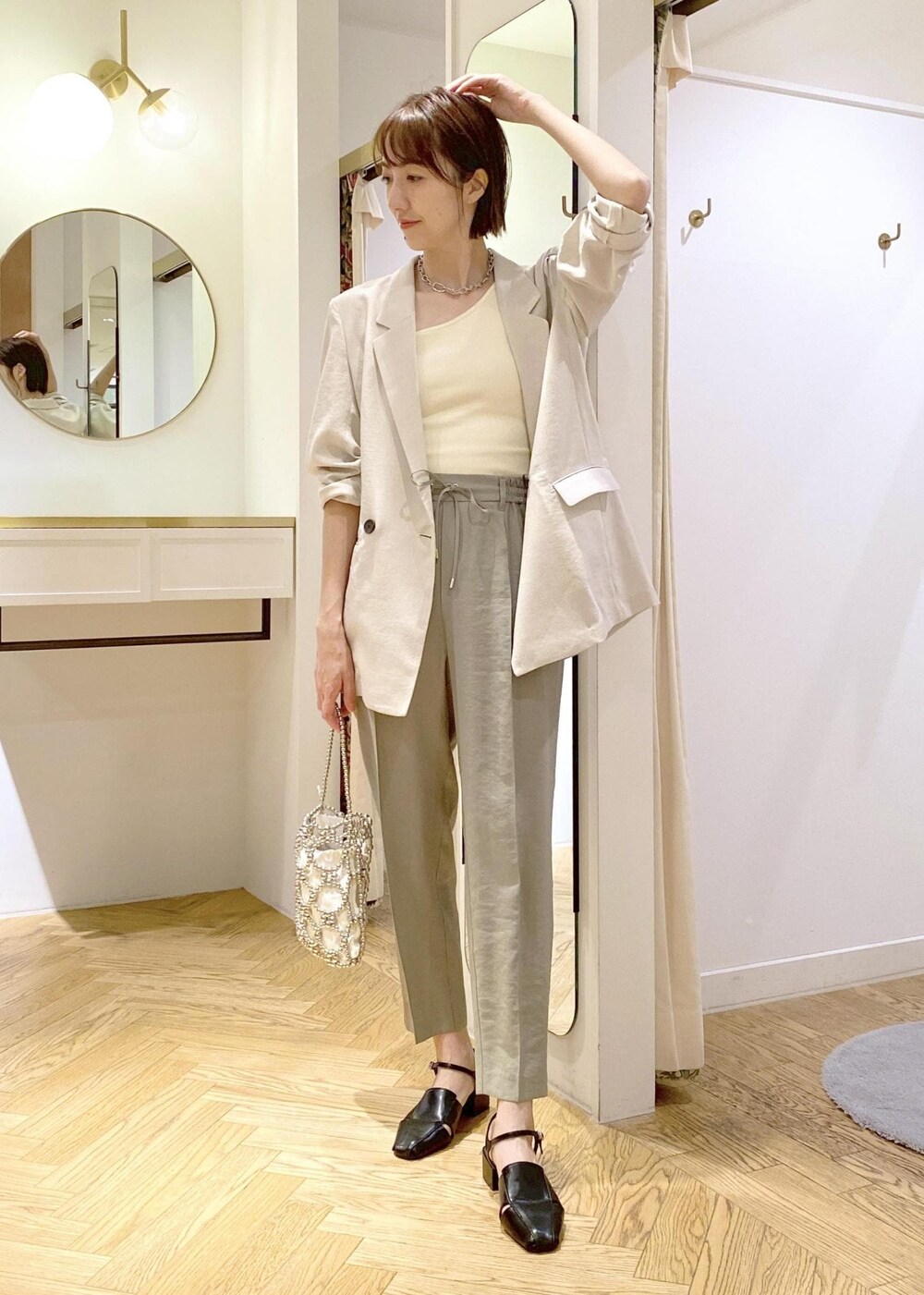 ホワイト系のタンクトップ、ブラック系のサンダル、グリーン系のスラックスを着用したレディースの春コーディネートの5枚目の写真