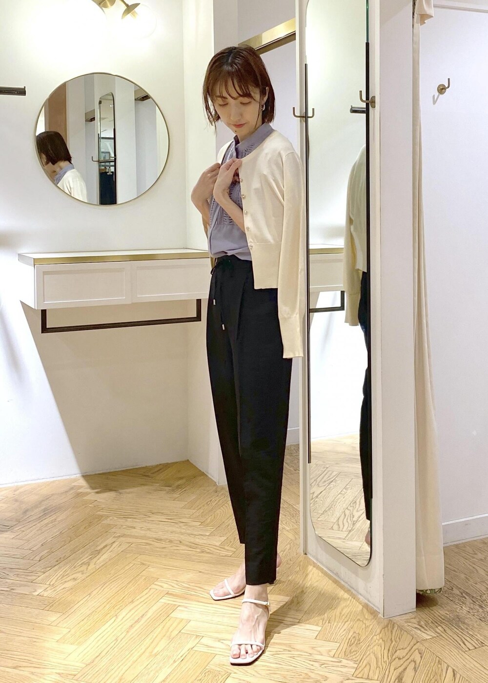 ブラック系のハンドバッグ、ホワイト系のカーディガン/ボレロ、ブラック系のスラックスを着用したレディースの夏コーディネートの5枚目の写真