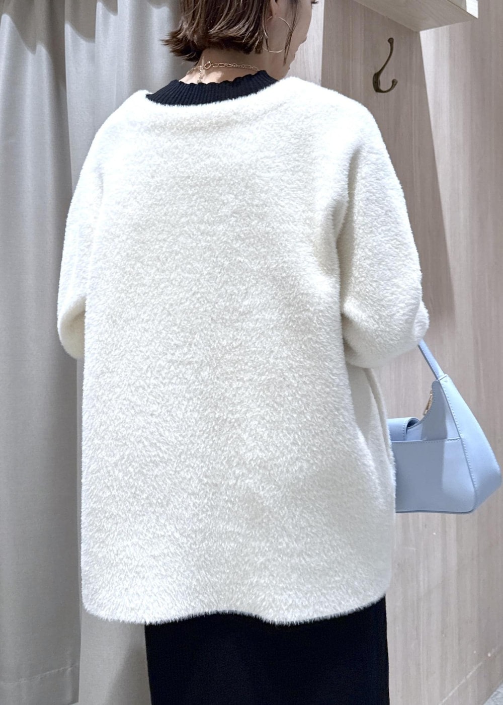 ブルー系のハンドバッグ、ホワイト系のノーカラージャケット、ブラック系のブーツを着用したレディースの秋コーディネートの10枚目の写真