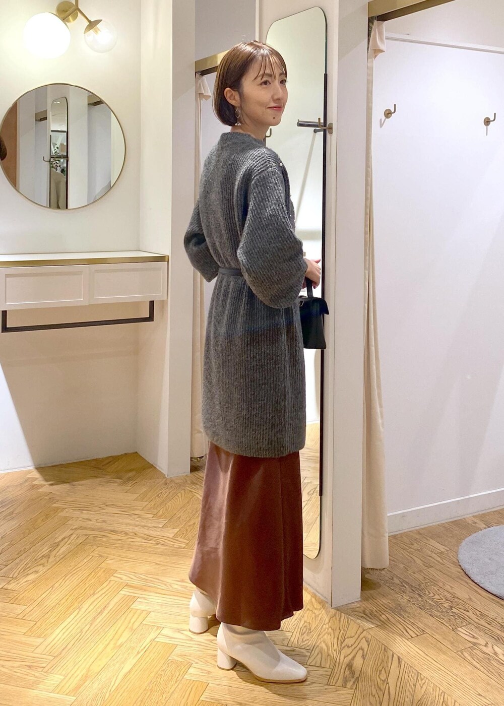 ホワイト系のブーツ、ブラウン系のスカート、グレー系のワンピースを着用したレディースの冬コーディネートの2枚目の写真