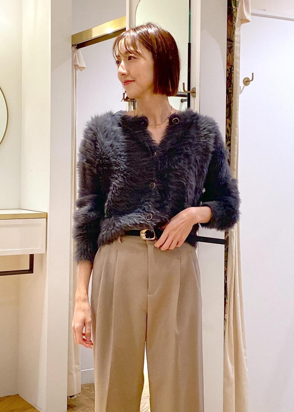 レッド系のトートバッグ、ベージュ系のスラックス、グレー系のカーディガン/ボレロを着用したレディースの冬コーディネートの7枚目の写真