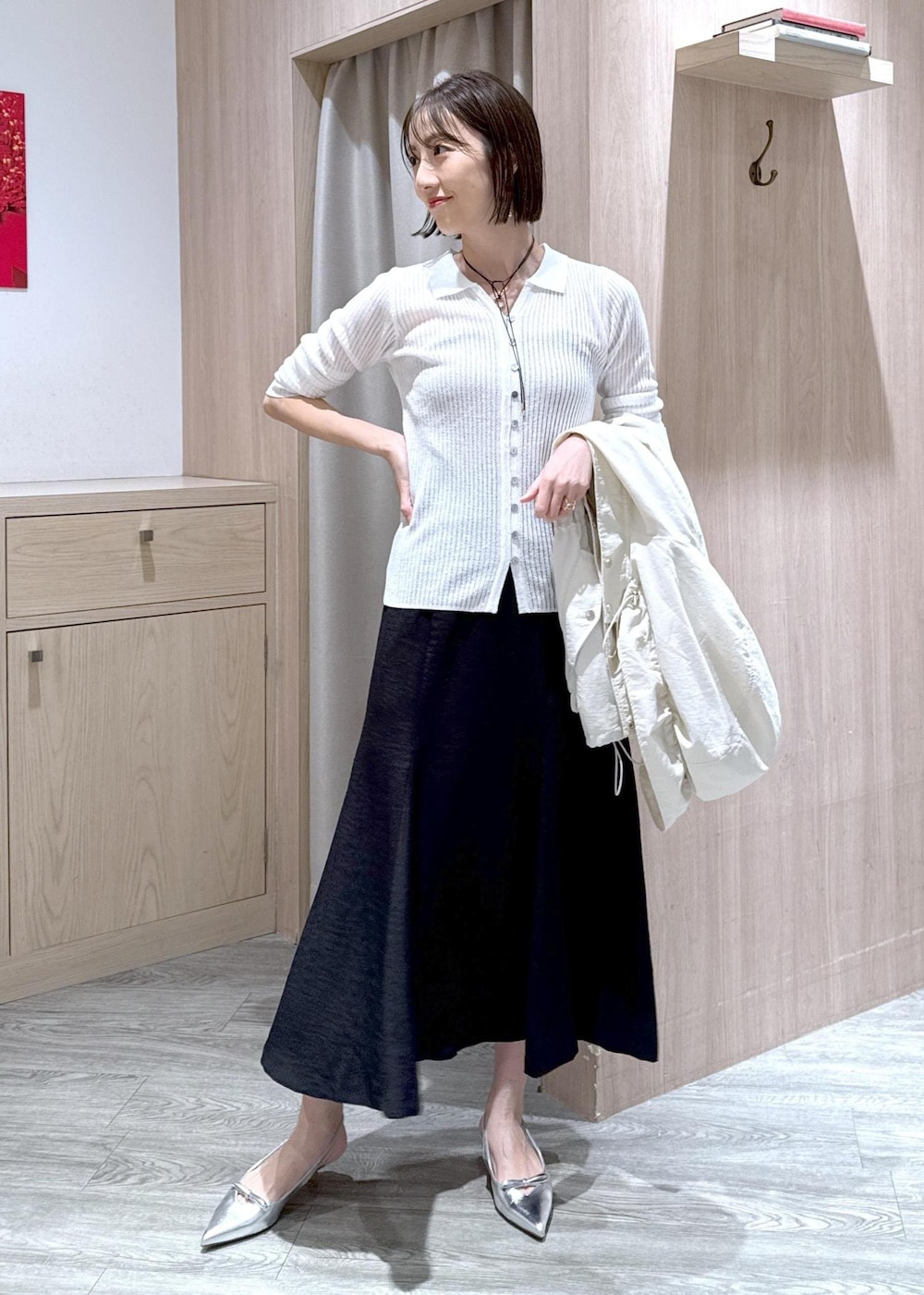 シルバー系のパンプス、ブラック系のスカート、ホワイト系のカーディガン/ボレロを着用したレディースの春コーディネートの9枚目の写真