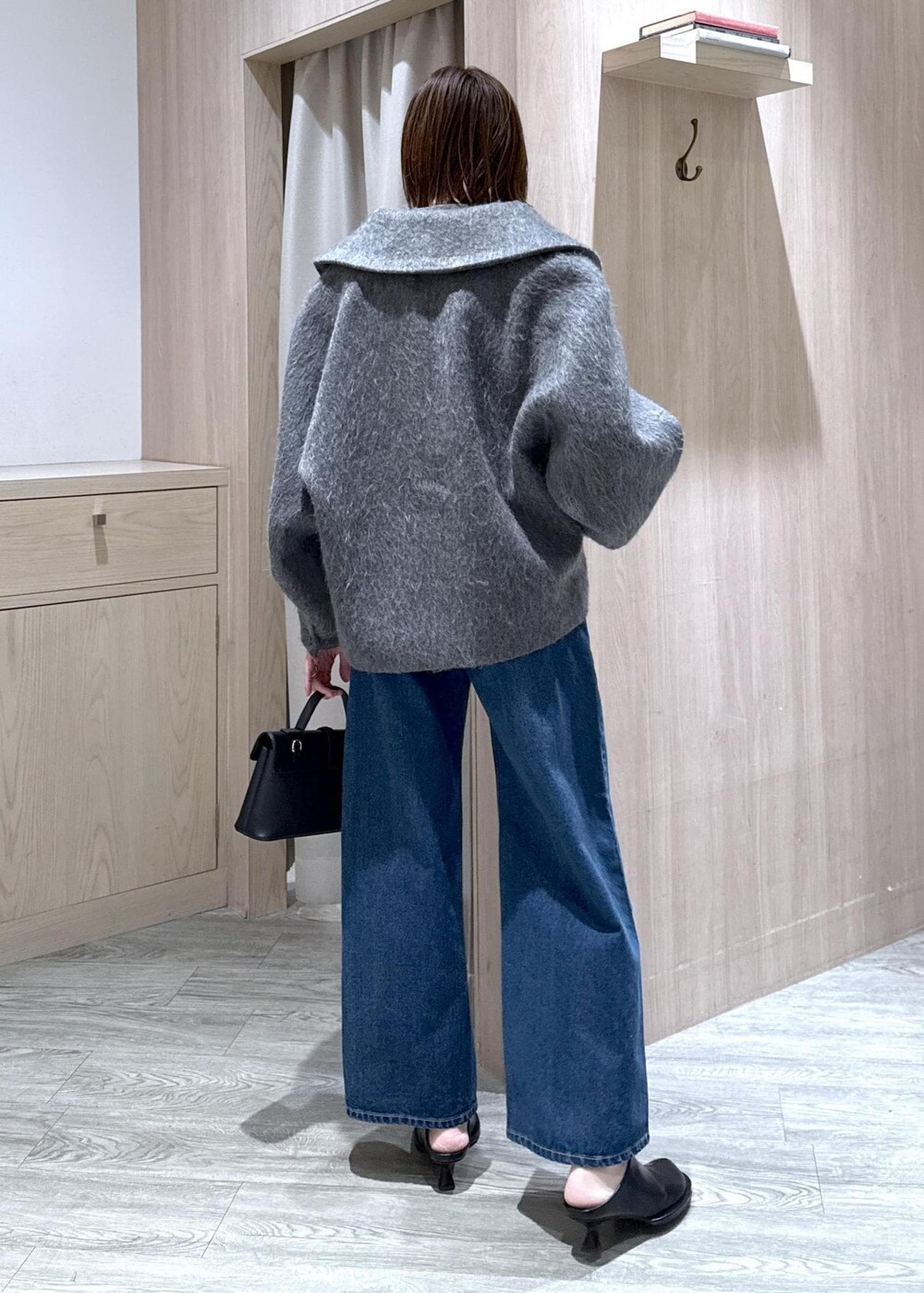 ブラック系のショルダーバッグ、ブルー系のデニムパンツ、グレー系のブルゾンを着用したレディースの冬コーディネートの3枚目の写真