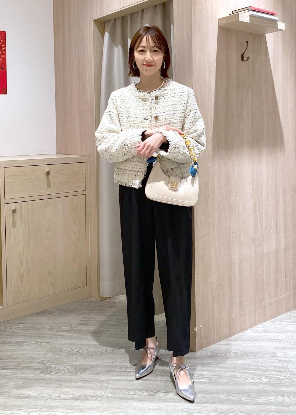 ホワイト系のハンドバッグ、シルバー系のパンプス、ブラック系のTシャツ/カットソーを着用したレディースの冬コーディネートの2枚目の写真
