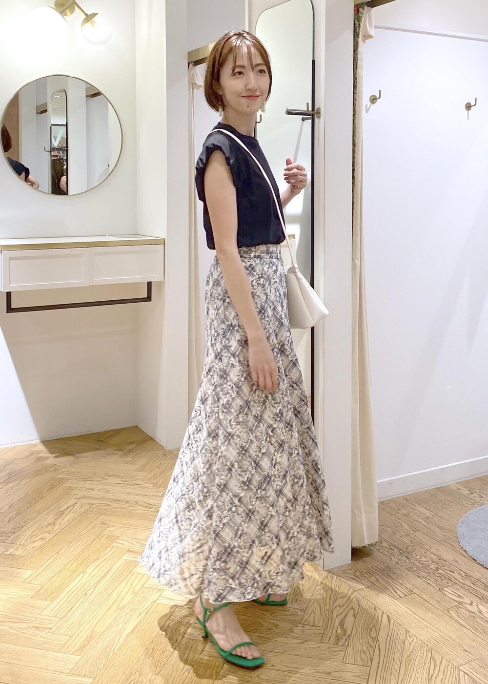 ブラック系のキャミソール、グリーン系のサンダル、ホワイト系のスカートを着用したレディースの夏コーディネートの2枚目の写真