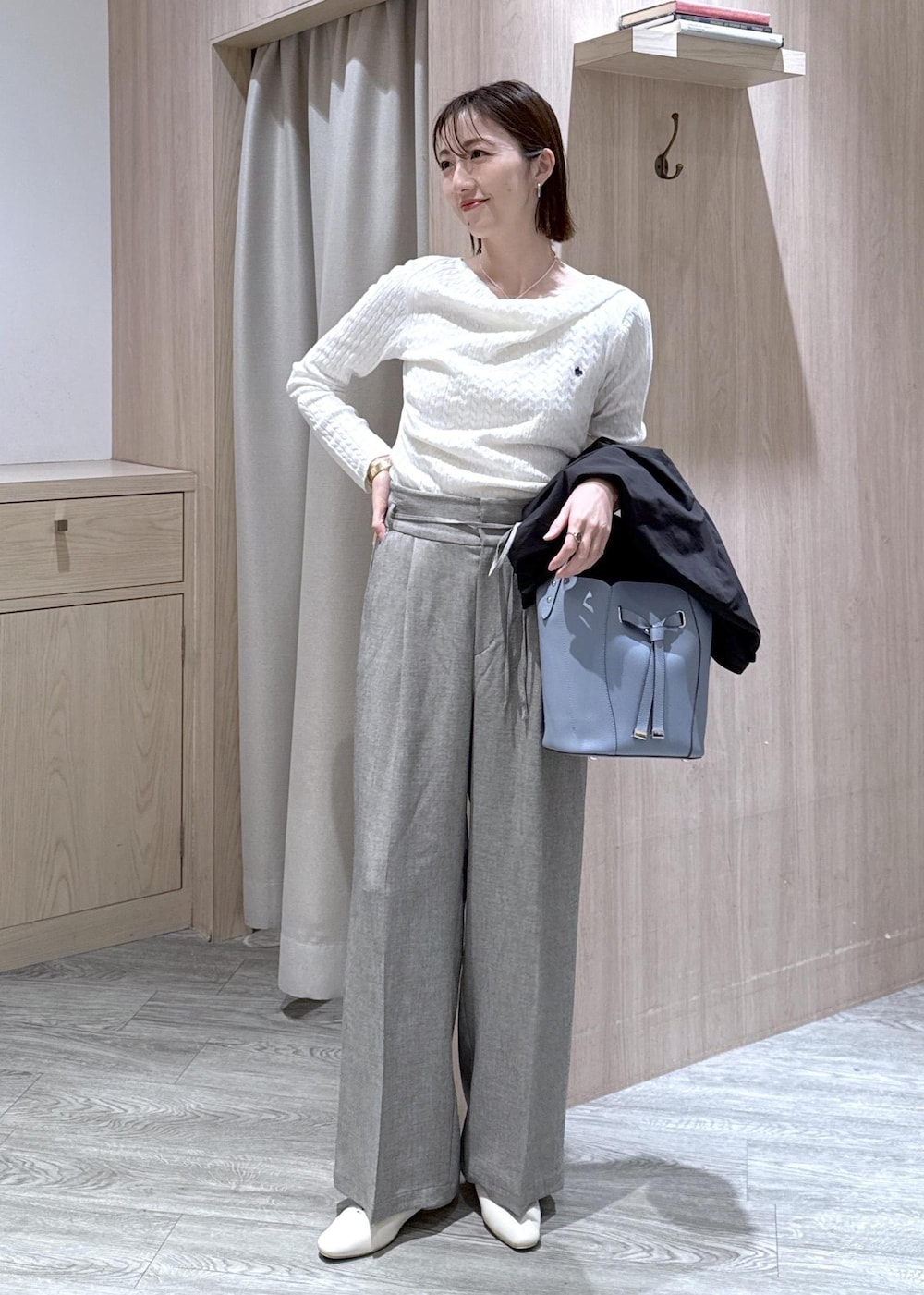 ブルー系のショルダーバッグ、ホワイト系のパンプス、ブラック系のブルゾンを着用したレディースの春コーディネートの2枚目の写真