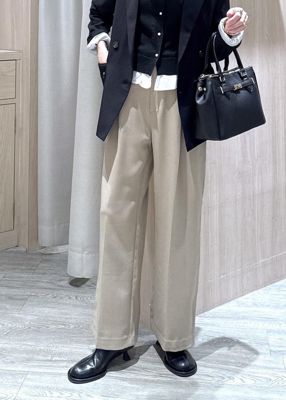 ブラック系のショルダーバッグ、ベージュ系のスラックス、ブラック系のテーラードジャケットを着用したレディースの冬コーディネートの3枚目の写真