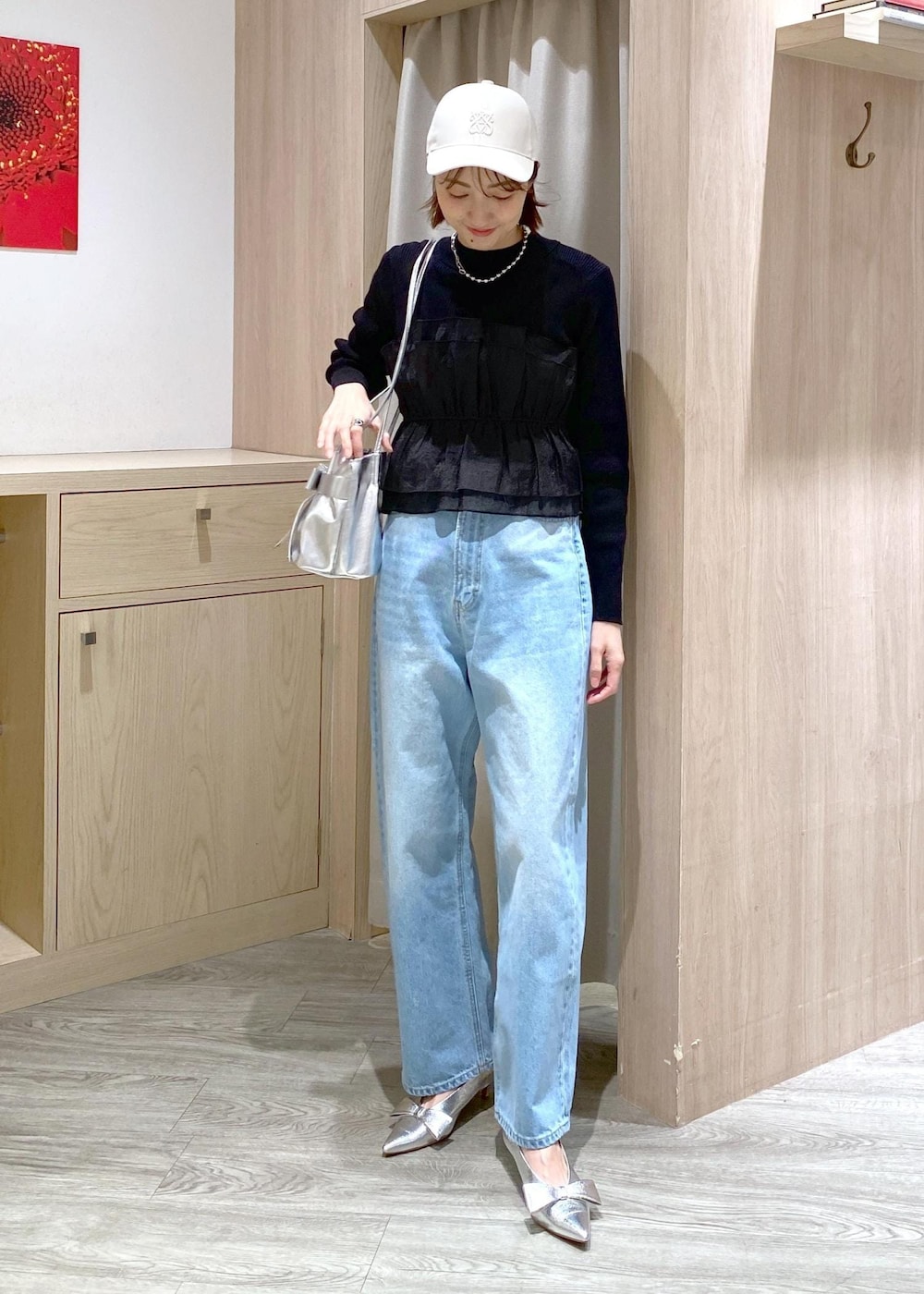 シルバー系のパンプス、ブラック系のニット/セーター、シルバー系のショルダーバッグを着用したレディースの冬コーディネートの2枚目の写真