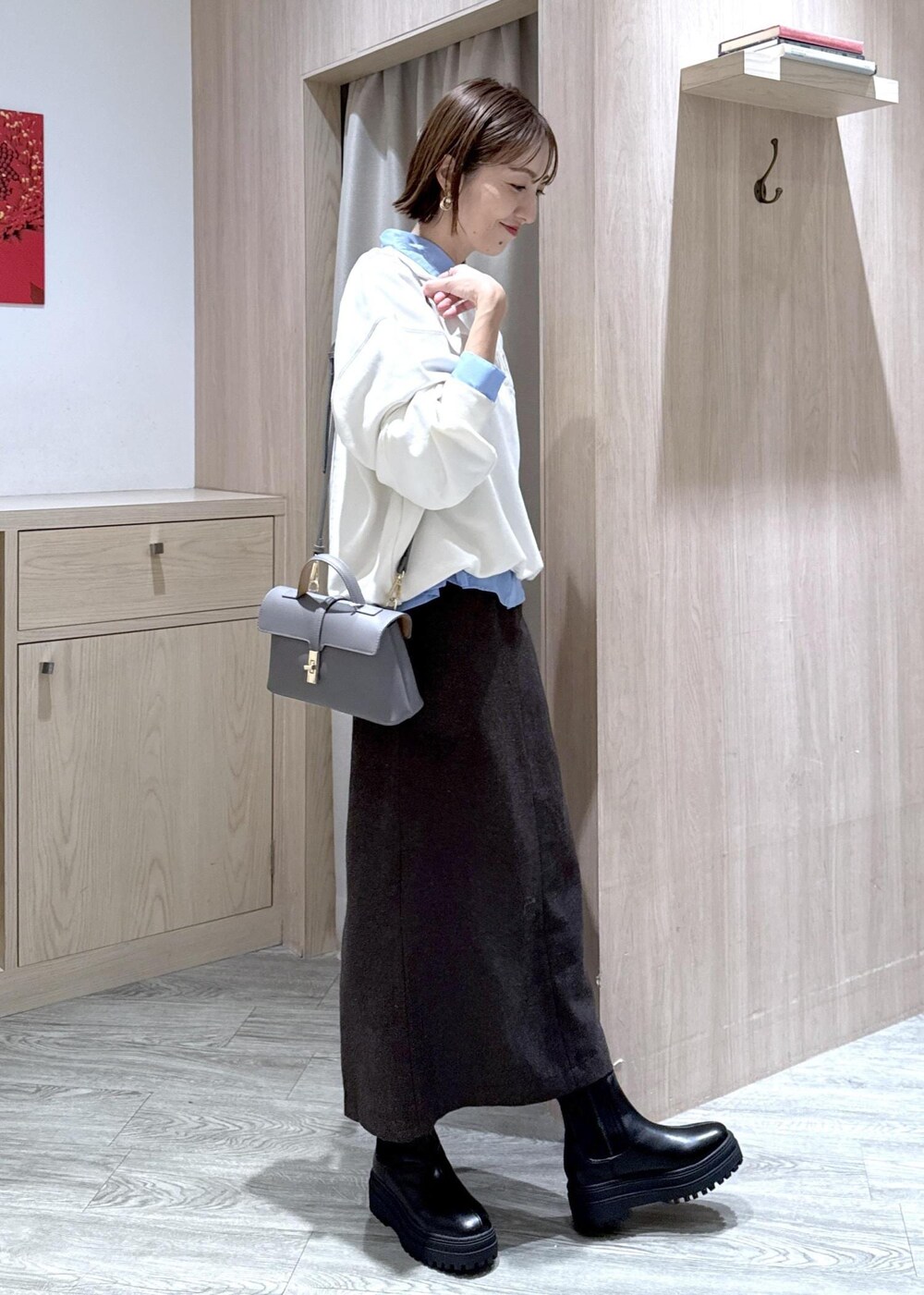 グレー系のショルダーバッグ、ブラック系のブーツ、ブラウン系のスカートを着用したレディースの秋コーディネートの4枚目の写真
