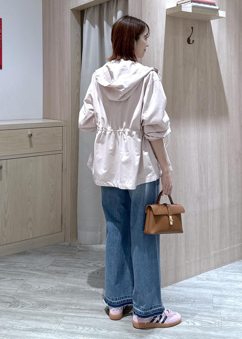 イエロー系のショルダーバッグ、ピンク系のナイロンジャケット、ブルー系のデニムパンツを着用したレディースの春コーディネートの3枚目の写真