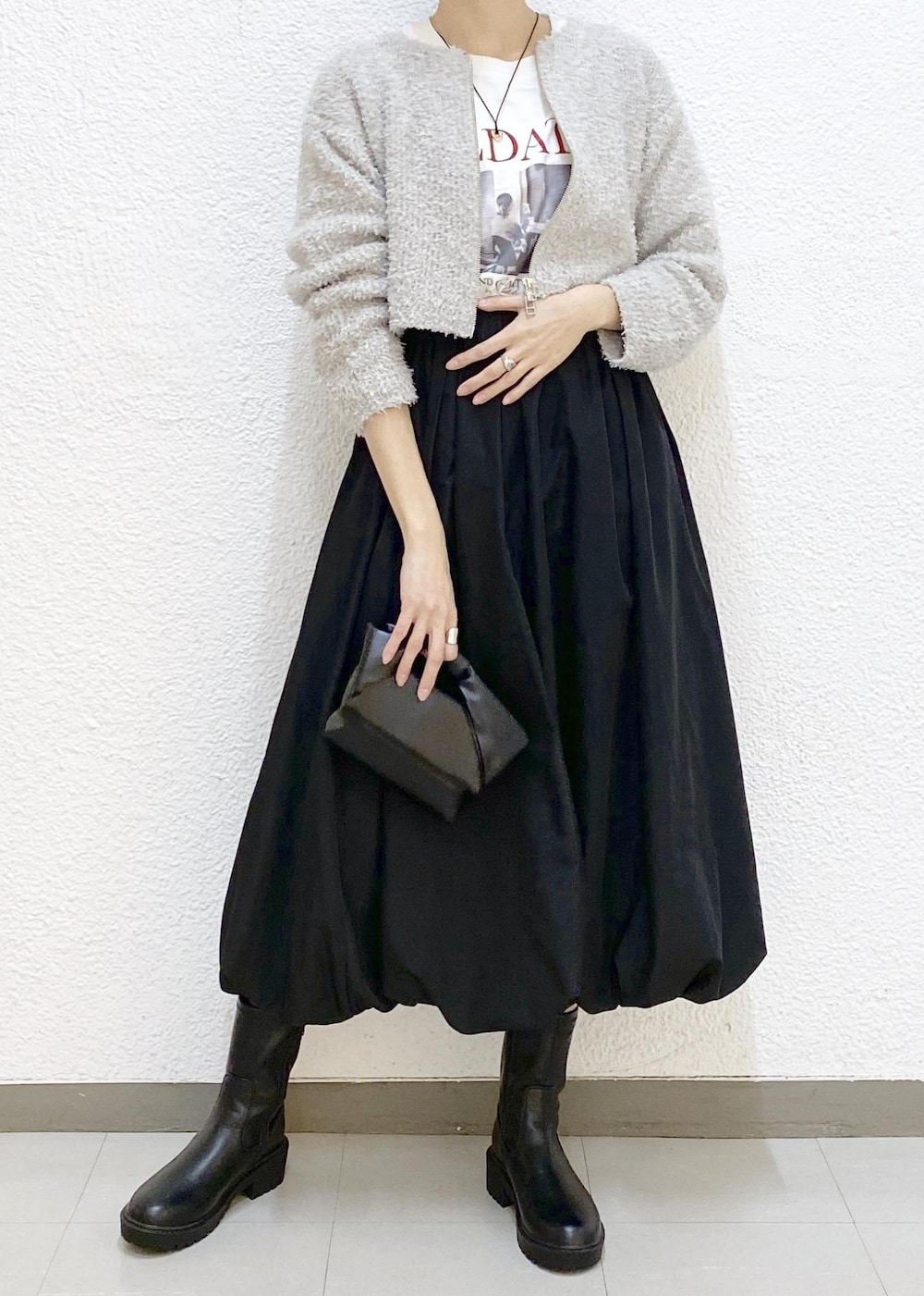 ホワイト系のTシャツ/カットソー、ブラック系のブーツ、ブラック系のスカートを着用したレディースの冬コーディネートの3枚目の写真