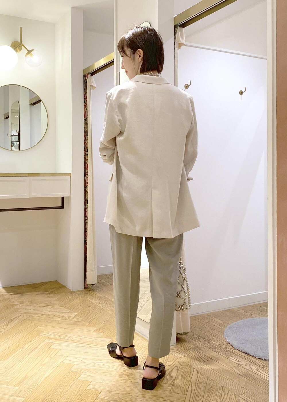 ホワイト系のタンクトップ、ブラック系のサンダル、グリーン系のスラックスを着用したレディースの春コーディネートの3枚目の写真