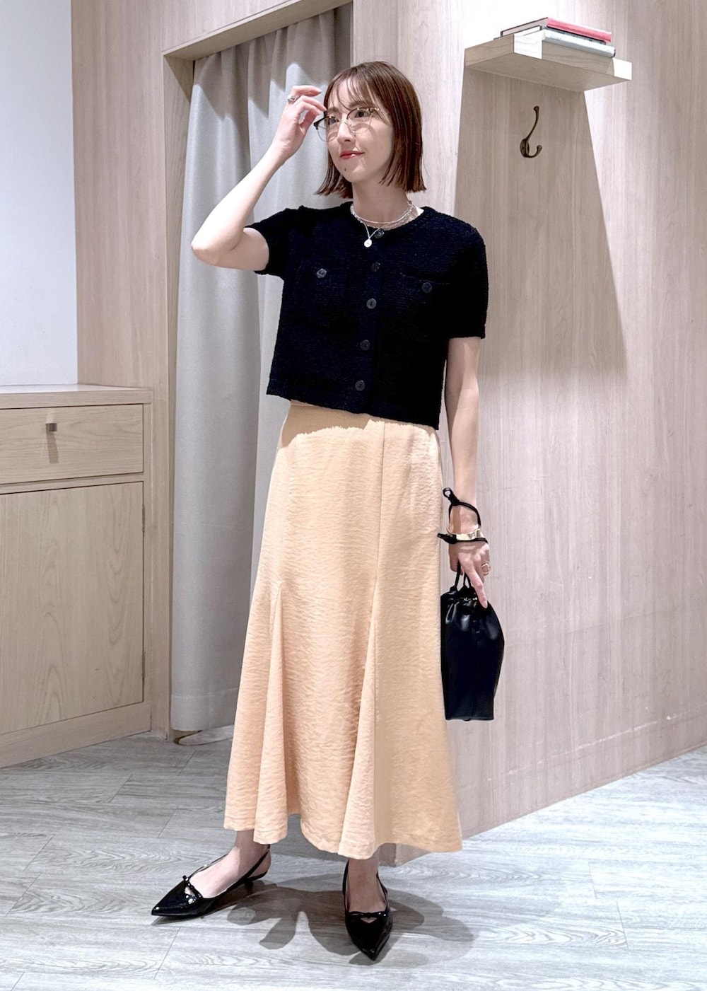 ブラック系のパンプス、オレンジ系のスカート、ブラック系のハンドバッグを着用したレディースの春コーディネートの2枚目の写真