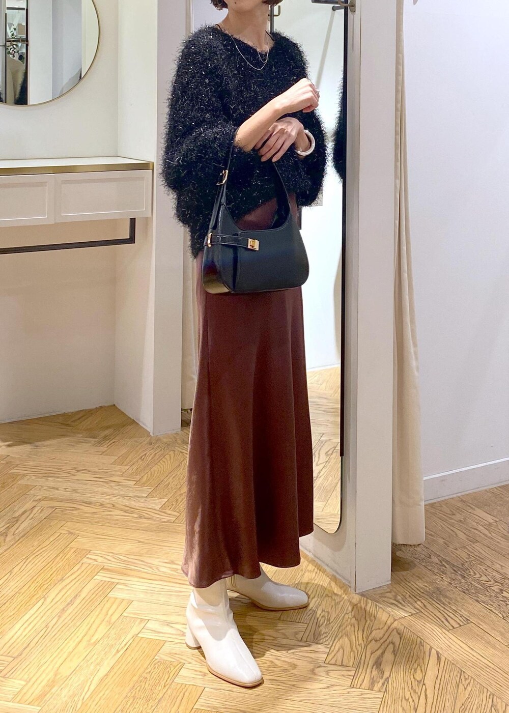 ホワイト系のブーツ、ブラック系のハンドバッグ、ブラック系のニット/セーターを着用したレディースの冬コーディネートの4枚目の写真