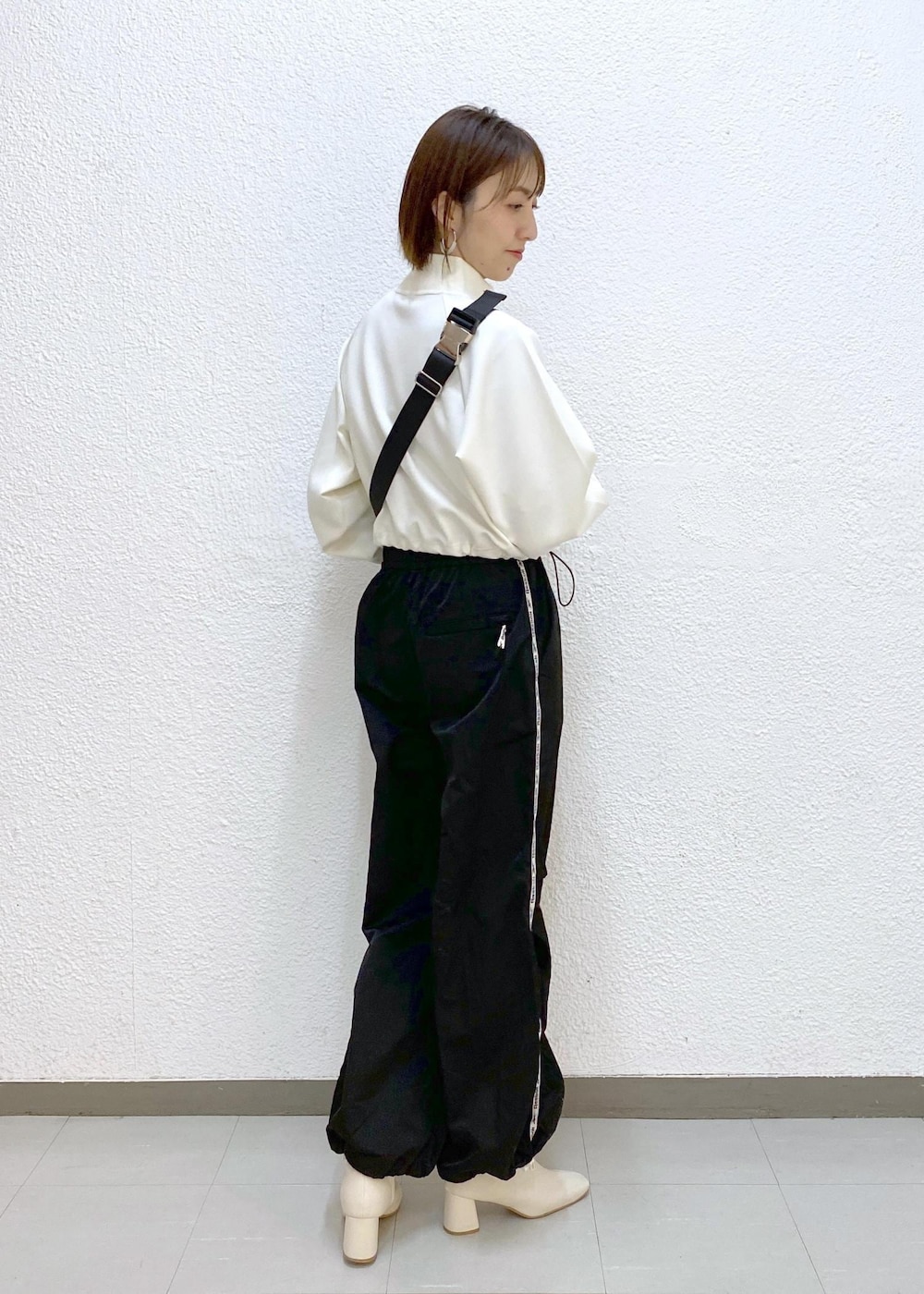 ブラウン系のボディバッグ/ウエストポーチ、ブラック系のその他パンツ、ホワイト系のその他トップスを着用したレディースの冬コーディネートの3枚目の写真