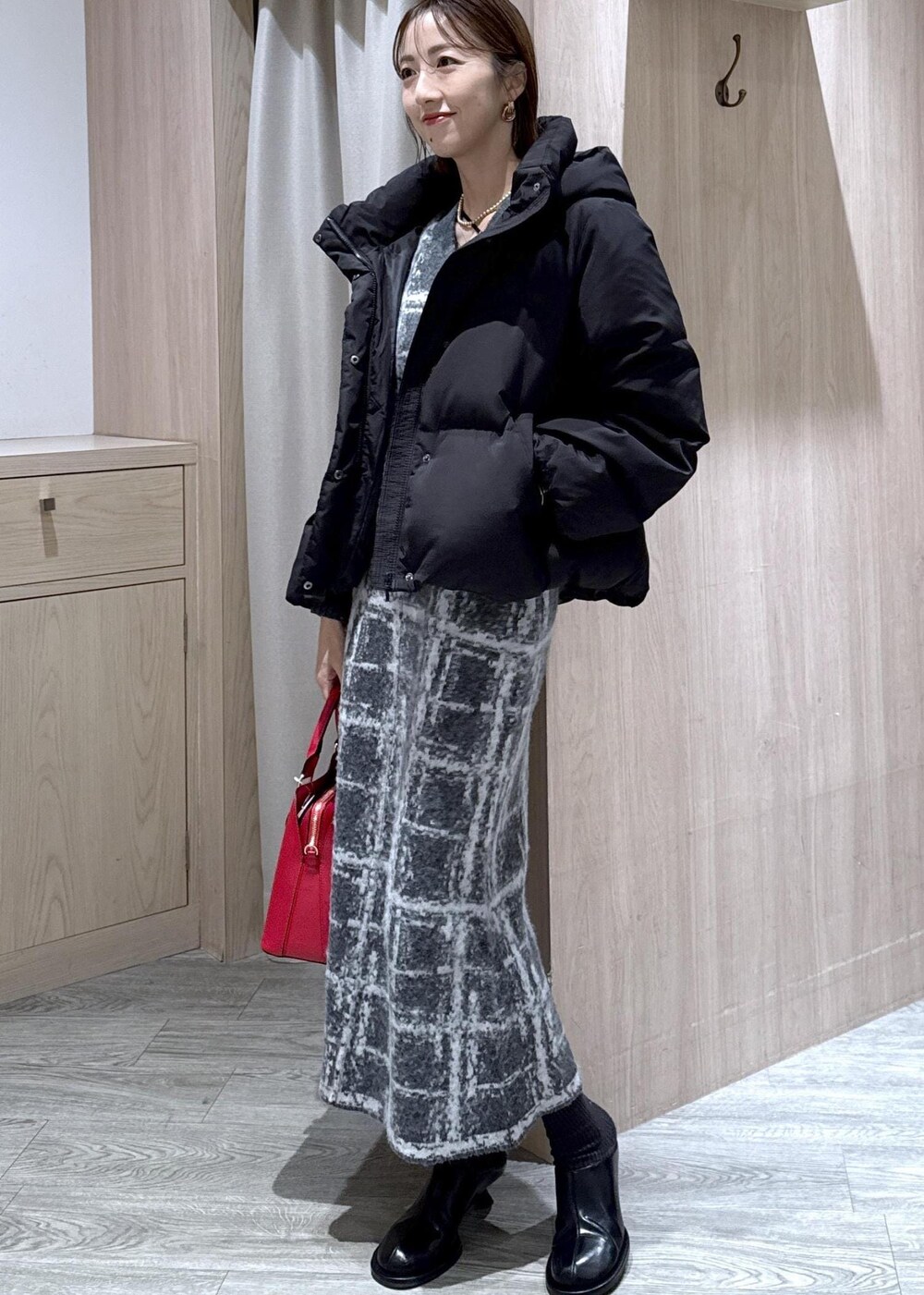 レッド系のボストンバッグ、ブラック系のダウンジャケット/コート、グレー系のスカートを着用したレディースの冬コーディネートの5枚目の写真