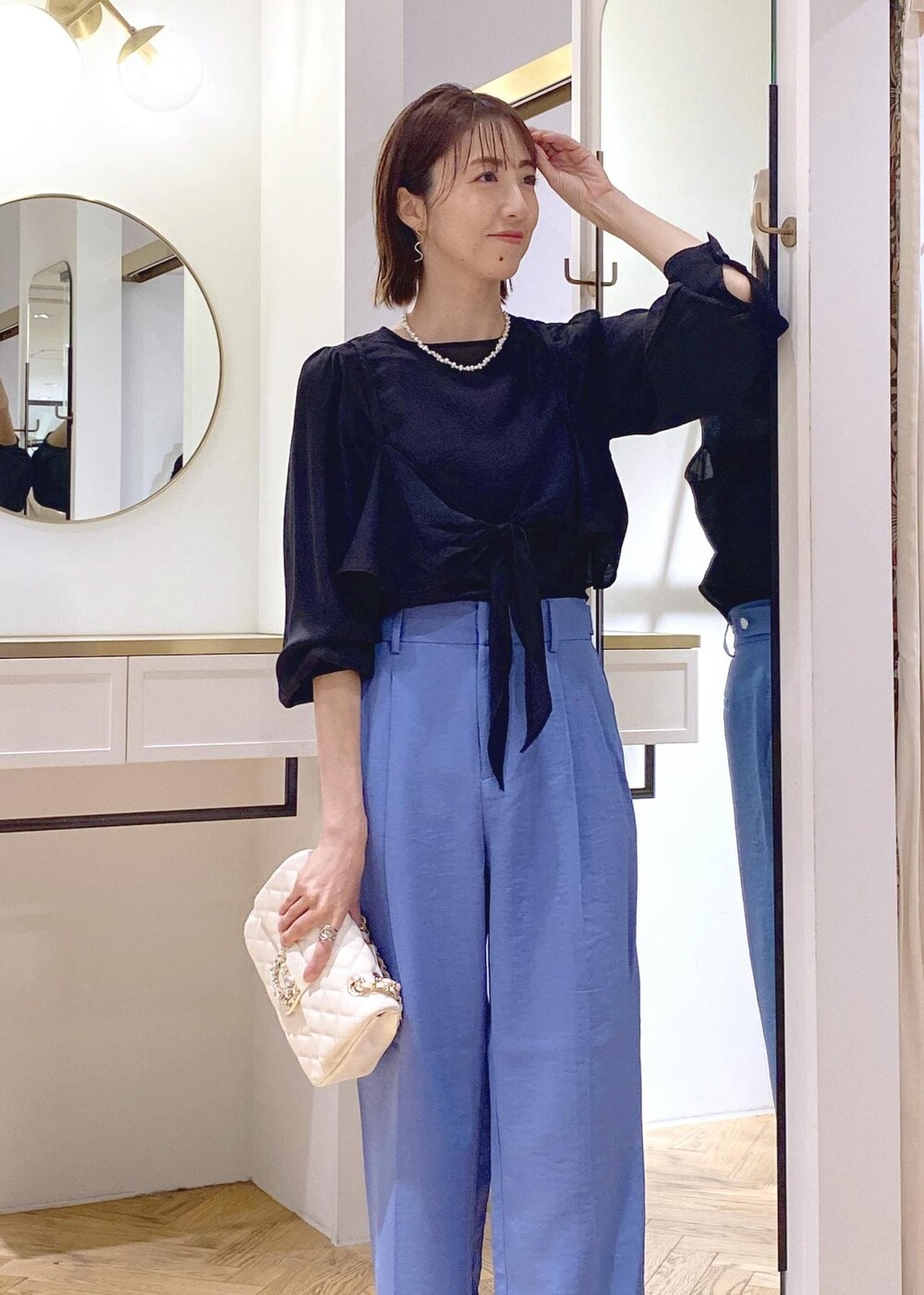 ホワイト系のショルダーバッグ、ブルー系のスラックス、ブラック系のシャツ/ブラウスを着用したレディースの春コーディネートの4枚目の写真