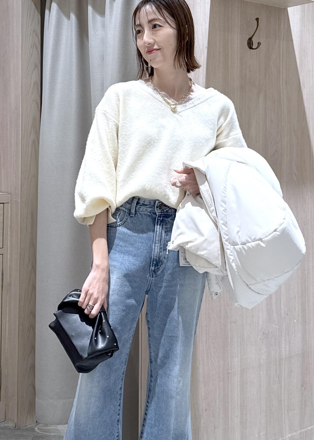 ホワイト系のダウンジャケット/コート、ブラック系のショルダーバッグ、ホワイト系のニット/セーターを着用したレディースの冬コーディネートの6枚目の写真