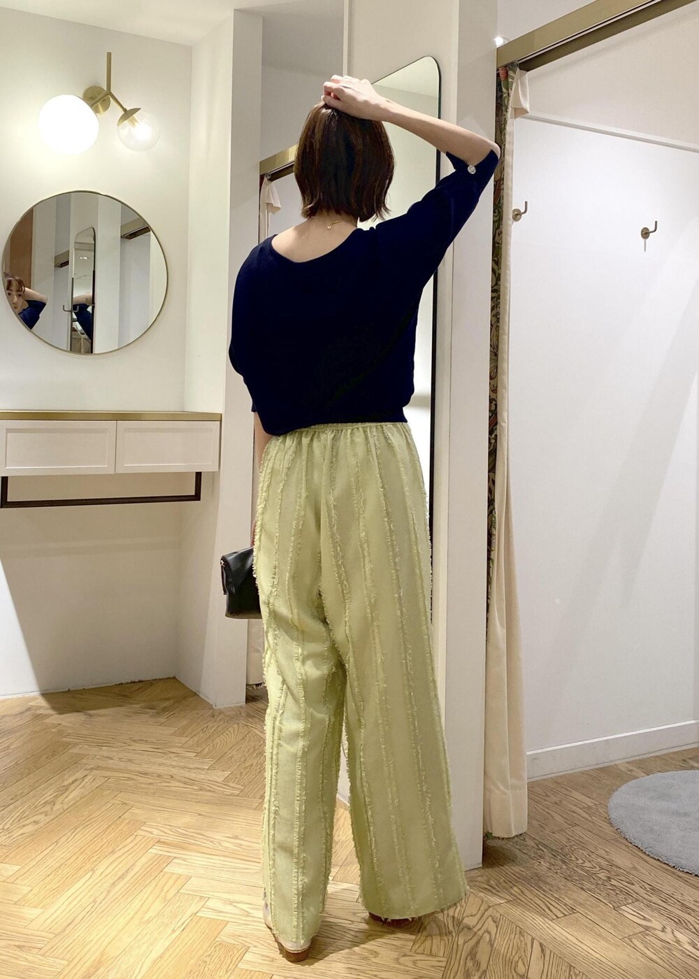 シルバー系のパンプス、グリーン系のスラックス、ブラック系のショルダーバッグを着用したレディースの春コーディネートの3枚目の写真