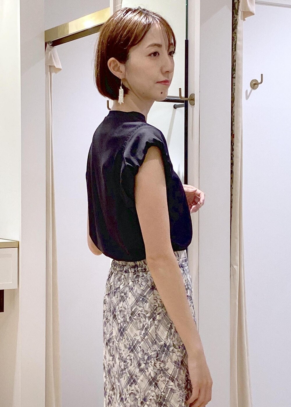 ブラック系のキャミソール、グリーン系のサンダル、ホワイト系のスカートを着用したレディースの夏コーディネートの6枚目の写真