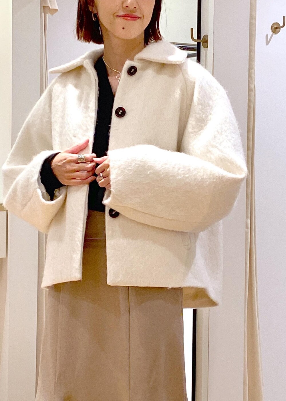 ホワイト系のブーツ、ベージュ系のスカート、ホワイト系のその他アウターを着用したレディースの秋コーディネートの8枚目の写真