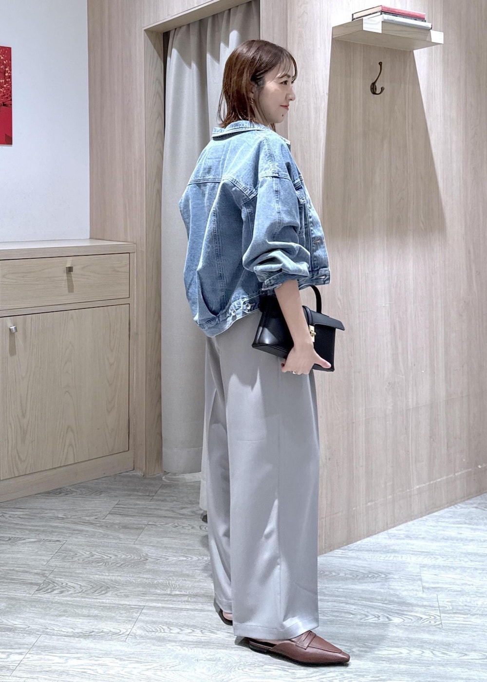 ブラック系のショルダーバッグ、ブルー系のデニムジャケット、グレー系のスラックスを着用したレディースの春コーディネートの3枚目の写真