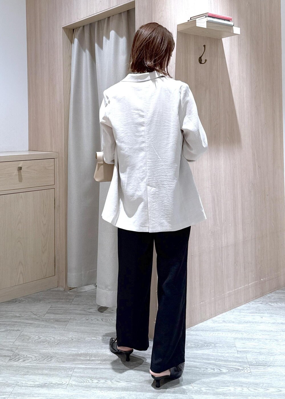 ベージュ系のショルダーバッグ、ブラック系のパンプス、ホワイト系のテーラードジャケットを着用したレディースの春コーディネートの5枚目の写真