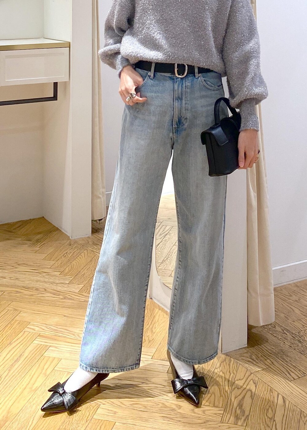 ブラック系のパンプス、グレー系のニット/セーター、ブルー系のデニムパンツを着用したレディースの冬コーディネートの7枚目の写真