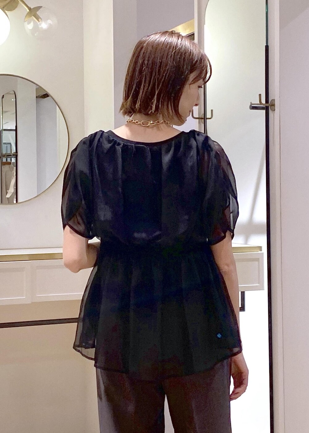 ブラック系のサンダル、ブラック系のハンドバッグ、グレー系のスラックスを着用したレディースの夏コーディネートの5枚目の写真