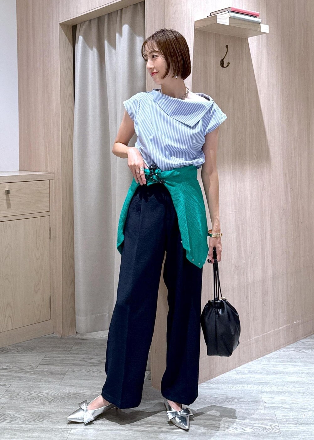 シルバー系のパンプス、ブラック系のハンドバッグ、ブルー系のスラックスを着用したレディースの夏コーディネートの10枚目の写真