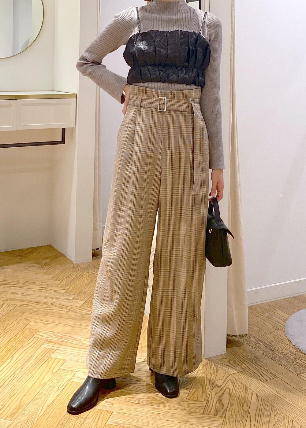 ブラック系のショルダーバッグ、ブラック系のブーツ、ベージュ系のスラックスを着用したレディースの秋コーディネートの5枚目の写真