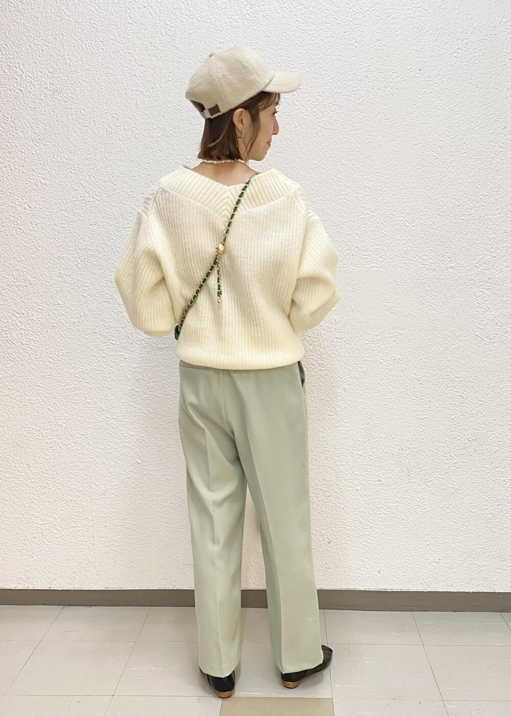 グリーン系のスラックス、グリーン系のショルダーバッグ、ホワイト系のニット/セーターを着用したレディースの冬コーディネートの2枚目の写真