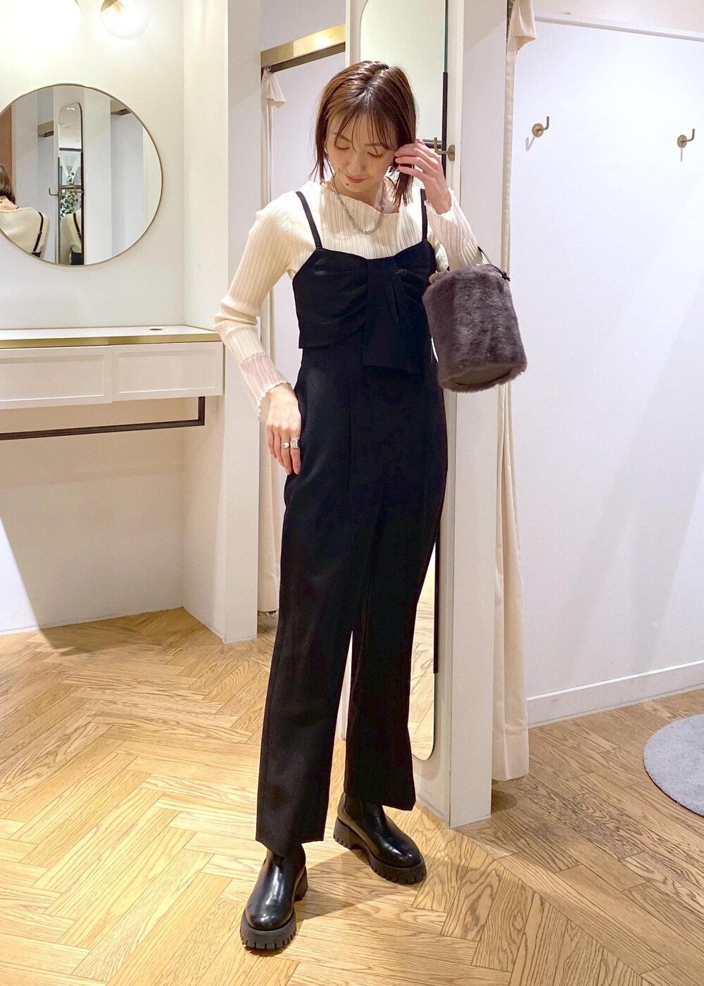 グレー系のショルダーバッグ、ブラック系のサロペット/オーバーオール、ホワイト系のニット/セーターを着用したレディースの冬コーディネートの2枚目の写真