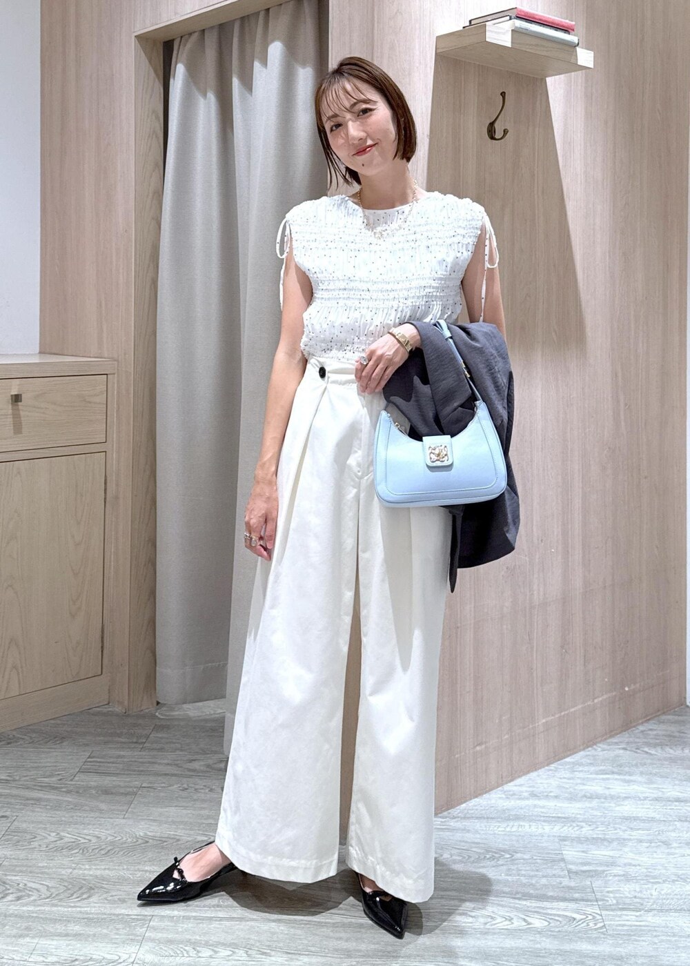 ブルー系のハンドバッグ、ブラック系のパンプス、ホワイト系のシャツ/ブラウスを着用したレディースの夏コーディネートの6枚目の写真