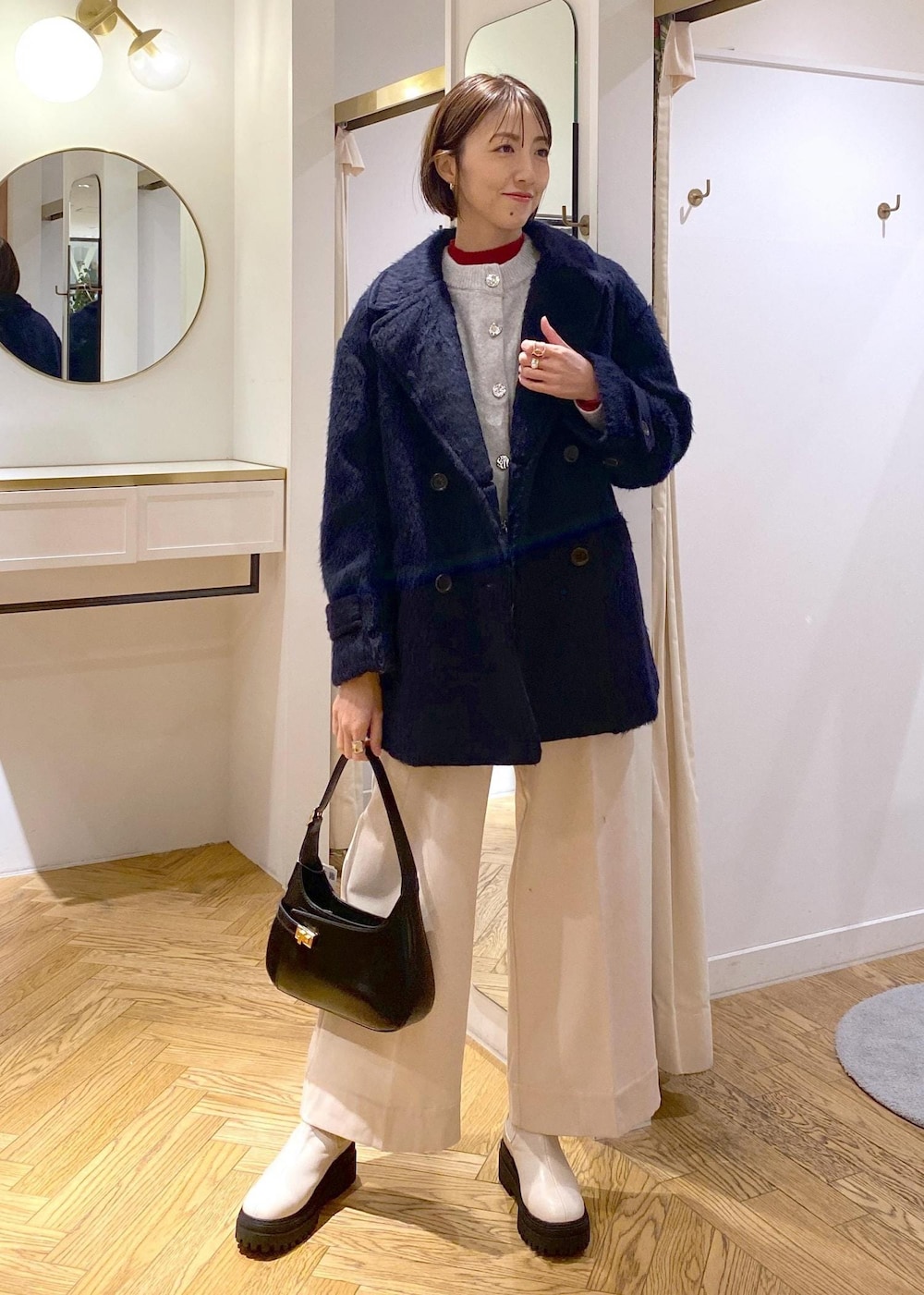 ホワイト系のブーツ、グレー系のカーディガン/ボレロ、レッド系のニット/セーターを着用したレディースの冬コーディネートの2枚目の写真